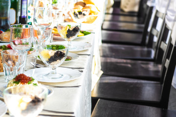 A salad in a transparent bowl stands on a festive served wedding table lit by bright sunlight. Top view