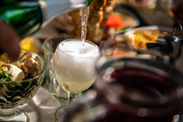 champagne is poured into a glass over a festive table with bright sunlight