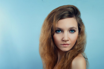 Fototapeta premium A beautiful fashionable portrait of a young girl with red hair and blue eyes. Beautiful model girl looks at the camera. The concept of makeup and hairstyles