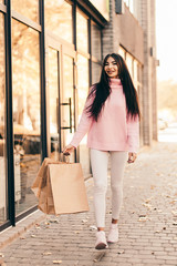 Beautiful smiling young woman with shopping bags on the street.
