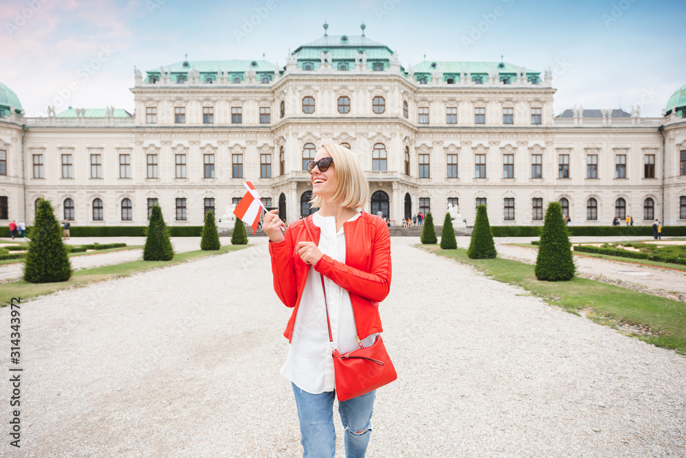 Wall mural a young female tourist with the austrian flag enjoys a tour of vienna in the garden of the belvedere