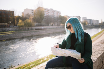 Explorer woman holding a map and sitting on stone fence