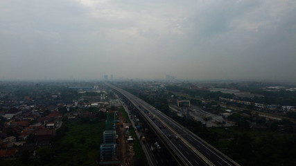 Fototapeta na wymiar BEKASI, WESTJAVA, INDONESIA : JANUARY 10 202 : Aerial drone view of highway multilevel junction road with moving cars after rainy. Cars are blurred