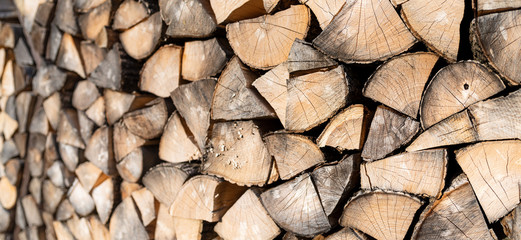 Fototapeta premium Oak firewood. Theme of alternative fuels and energy sources. Wide-angle banner background with copyspace