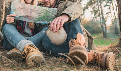 Travel couple camping with map in the forest. Concept of trekking, adventure and seasonal vacation.