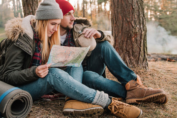 Fototapeta na wymiar Travel couple camping with map in the forest. Concept of trekking, adventure and seasonal vacation.