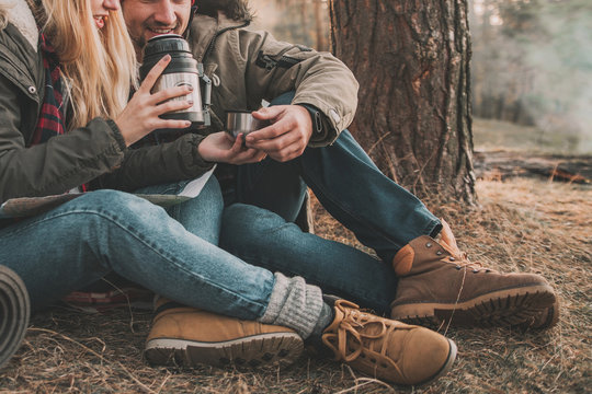 Travel Couple Camping With Thermos In The Forest. Concept Of Trekking, Adventure And Seasonal Vacation.