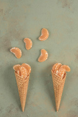 tangerine fruits in ice cream cones on green background