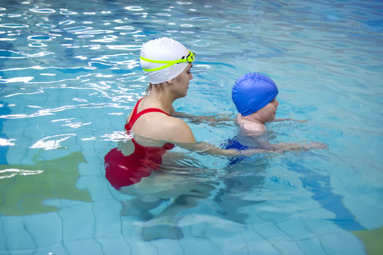 Little Boy Learns To Swim In An Individual Lesson With A Trainer