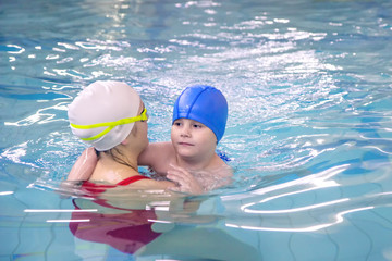 Little boy learns to swim in an individual lesson with a trainer