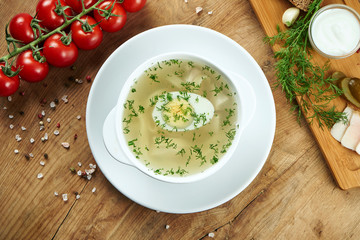 Dietary soup with chicken, boiled egg vegetables and parsley in compostion with ingridients on wooden background in white bowl. Top view tasty soup. Flat lay food