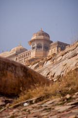 Detail of one of the towers of Amer Fort, close to Jaipur in India. Some grass and walls in the foreground of the picture taken on a sunny day.