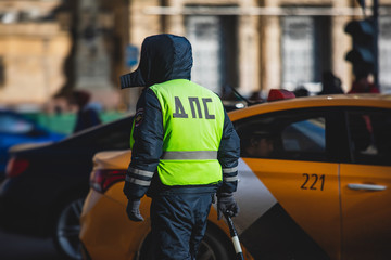 Fototapeta premium Russian Inspector of traffic police highway patrol regulates the movement of transport in the center of Moscow, in yellow vest jacket with a sign 