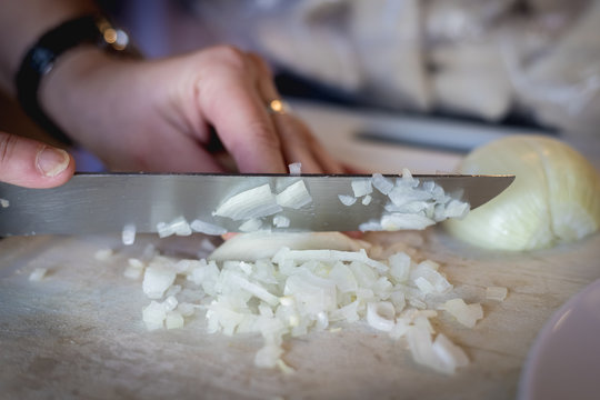 woman cuts onions on a white plastic board