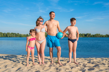 Happy family on the beach by the river. Lifestyle. Sports games on a sunny day. © Andrii