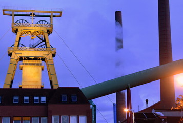 Nächtliches Bergwerk mit Förderturm, Schornsteinen und Nebel
