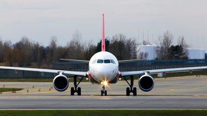 Big modern white aircraft preparing for take-off from the runway of the airport, front view