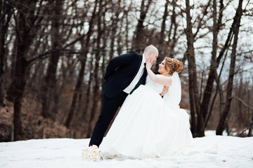 Young bride with groom dancing in the forest. Woman with long white dress and man in black suit with tie. Wedding, engagement rings exchange of young, dress, ring