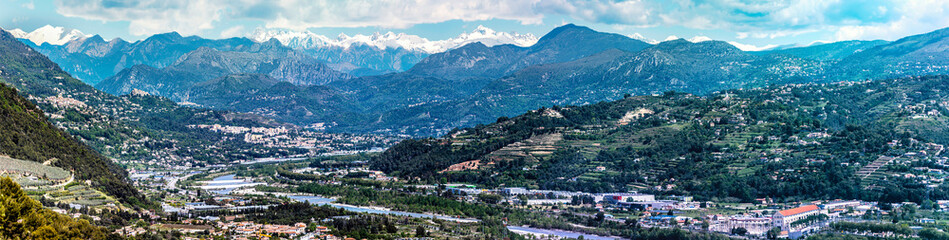 Panoramic view of Var Valley from Saint Laurent du Var village, the suburb of Nice city. Mountains of Mercantour National Park isa at background. French Riviera.