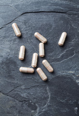 Carnitine capsules. Concept for a healthy dietary supplementation. Dark stone background. Top view. 