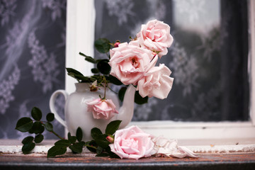 roses in   vase from   teapot on  windowsill.