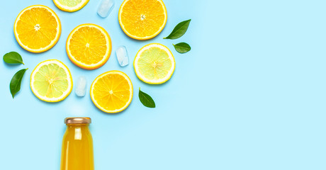 Flat lay composition with glass bottles of juice or fresh, slices of fresh lemon and orange, green...