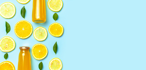 Flat lay composition with glass bottles of juice or fresh, slices of fresh lemon and orange, green...