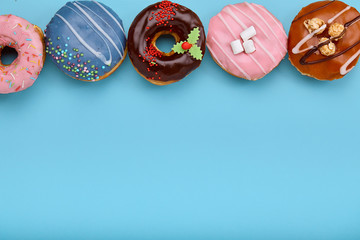 Top view of assorted donuts on blue background with copy space. Colorful donuts background. Various glazed doughnuts with sprinkles.