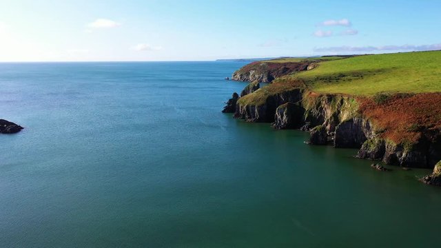 Aerial flying over costal cliffs during sunny day, pedestal movement.
