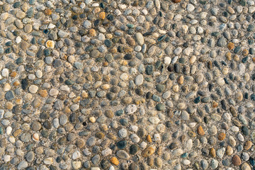 Texture and background with small pebbles, sidewalk on a street
