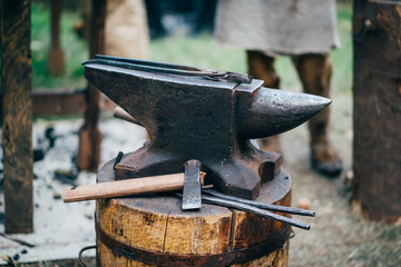 The hammer lies on the anvil in the forge. A craftsman forges metal. A blacksmith in old work...