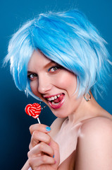 Cheerful glamorous woman  in blue wig with a lollipop in her hands