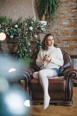 beautiful young girl in long socks near Christmas tree in winter wooden house. Christmas time, and happy New Year thematics