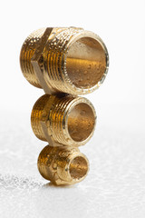 Closeup brass pipe fitting on white wet workshop table