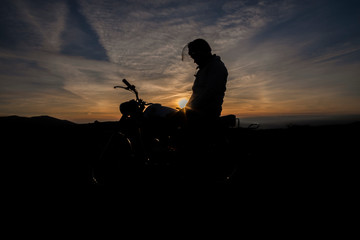 Silhueta de pessoa e moto ao por do sol