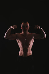 Portrait of young handsome sportsman bodybuilder over dark background