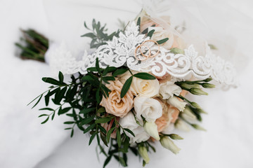 Obraz na płótnie Canvas Wedding rings are on the bridal veil and flowers