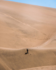 Fototapeta na wymiar silhouette of man practice sandboarding in the desert of Peru.
