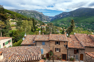 The Loup gorge as seen from the Church square of Le Bar-sur-Loup village in Southeastern France. Facades and roofs of old village houses are at foreground.