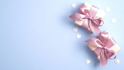 Valentine gift boxes with pink ribbon bow on pastel blue background with heart shaped confetti. Valentines or Mother day banner design. Flat lay, top view, copy space.