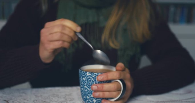 Woman with raynaud disease stirring her cup of coffee