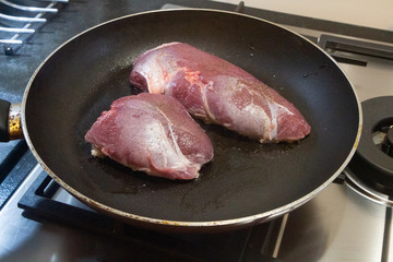 Duck breast grilling on gas in a frying pan