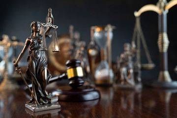 Obraz na płótnie Canvas Law and justice theme. Judge’s gavel, Themis statue, scale, hourglass and old clock on the shining wooden brown table and the gray background.