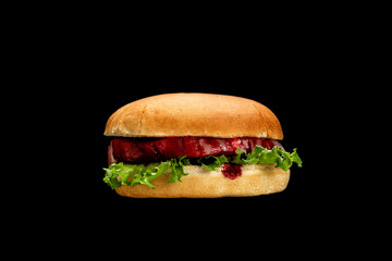 Disgusting burger with raw meat and blood isolated on black.