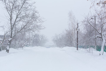 Winter, rural streets are covered with snow. Snow blizzard