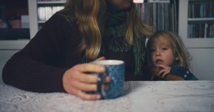Woman with raynaud disease drinking coffee with toddler
