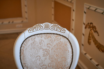 The back of an old classic chair, decorated with patterns of gold. Palace style in the interior.
