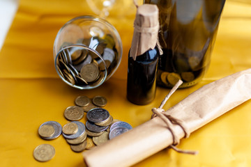 scroll of paper with wine bootle and glass with coins on yellow background