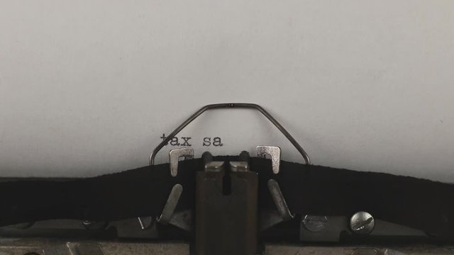 close-up typing a text tax saving, old vintage typewriter with a sheet of paper 