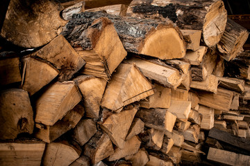 Stack of dry firewood, visible texture and cracks in the tree. Preparation of firewood for the winter. Eco-raw materials
